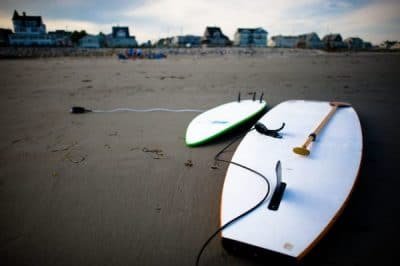 Two hard paddle boards lay face down in the sand at the beach