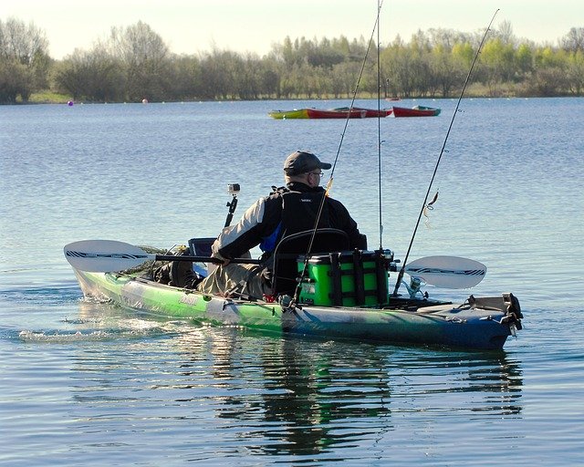 Man paddles a sit on top fishing kayak decked out with all the fishing gear