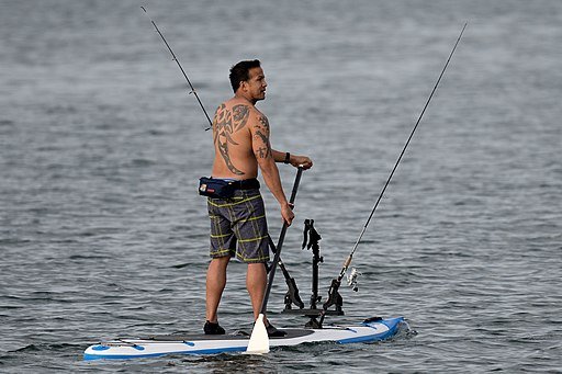 Man paddling his paddle board looking for a spot to do some SUP fishing