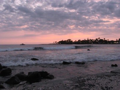 Sunset photo of waves lapping the shore of the Kona Coast