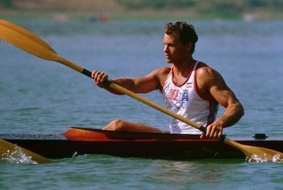 Fit, muscular Olympic paddler paddles his kayak