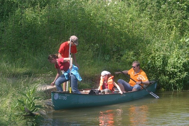 Mom, dad, and two teenagers land the canoe ashore after a canoe trip.