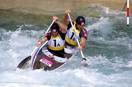 Olympic kayakers paddle a kayak in tandem