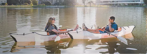 2 kayakers relaxing in a calm urban waterway in their Oru Inlet foldable kayaks